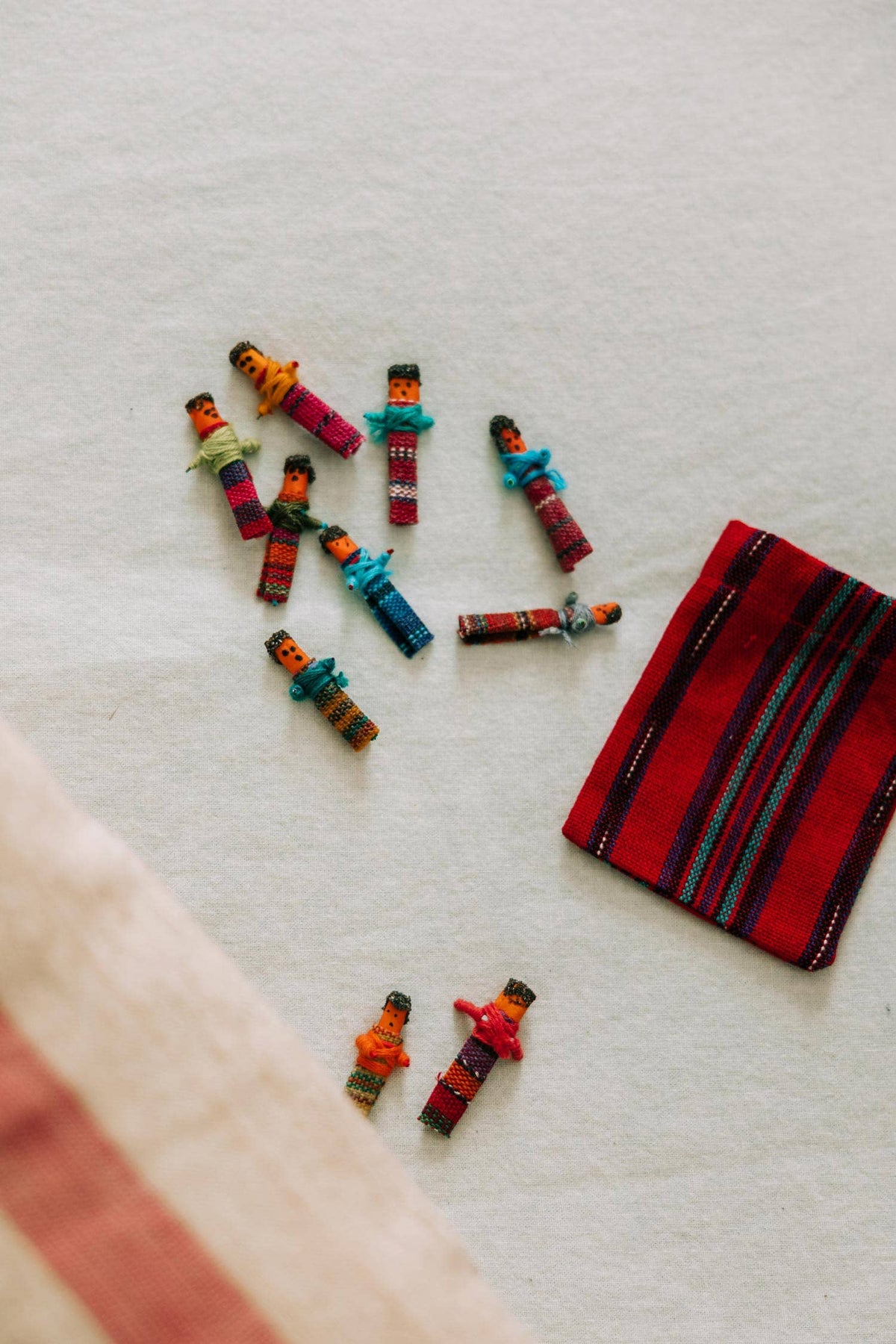 Colorful miniature figures on a textured surface with a red and black striped fabric.
