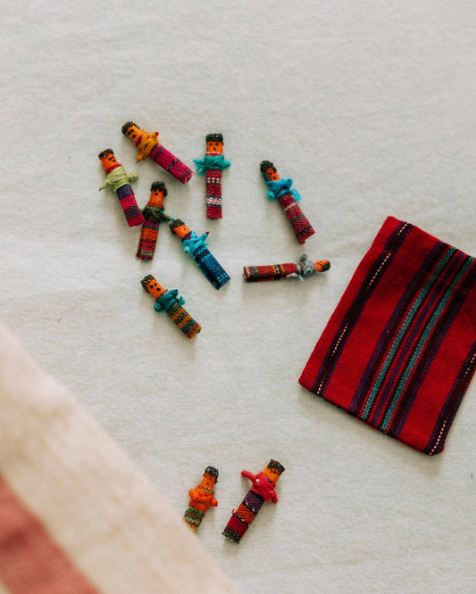 Colorful miniature figures on a textured surface with a red and black striped fabric.
