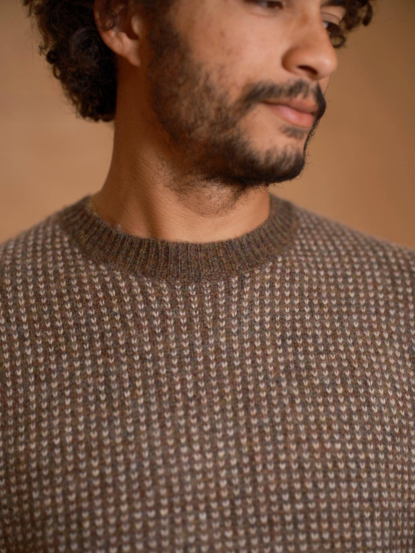 Man wearing a brown textured sweater against a beige background