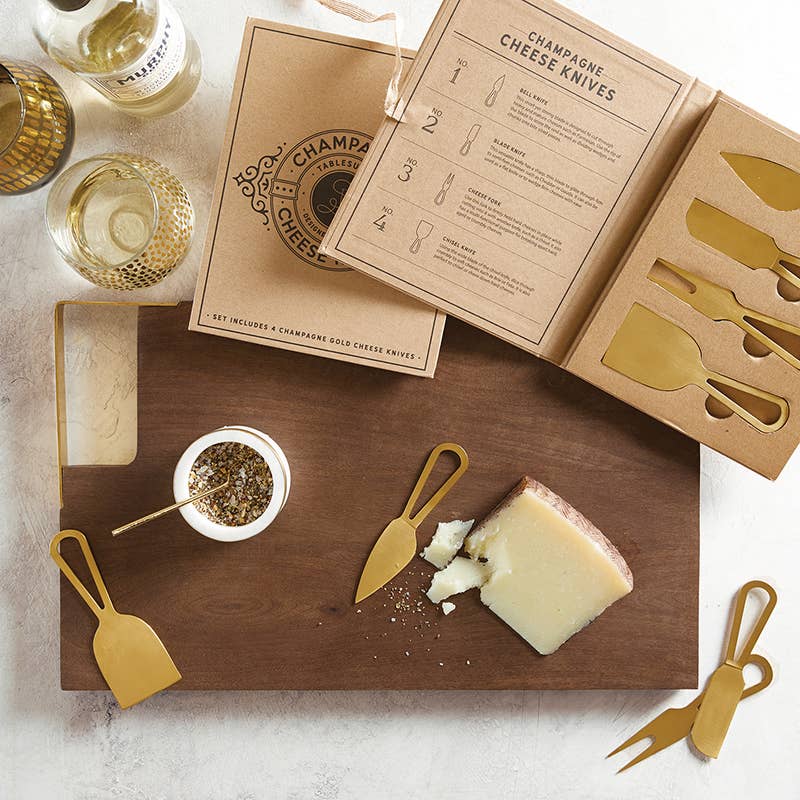 Wooden board with champagne cheese knives, cheese, and wine on a light background