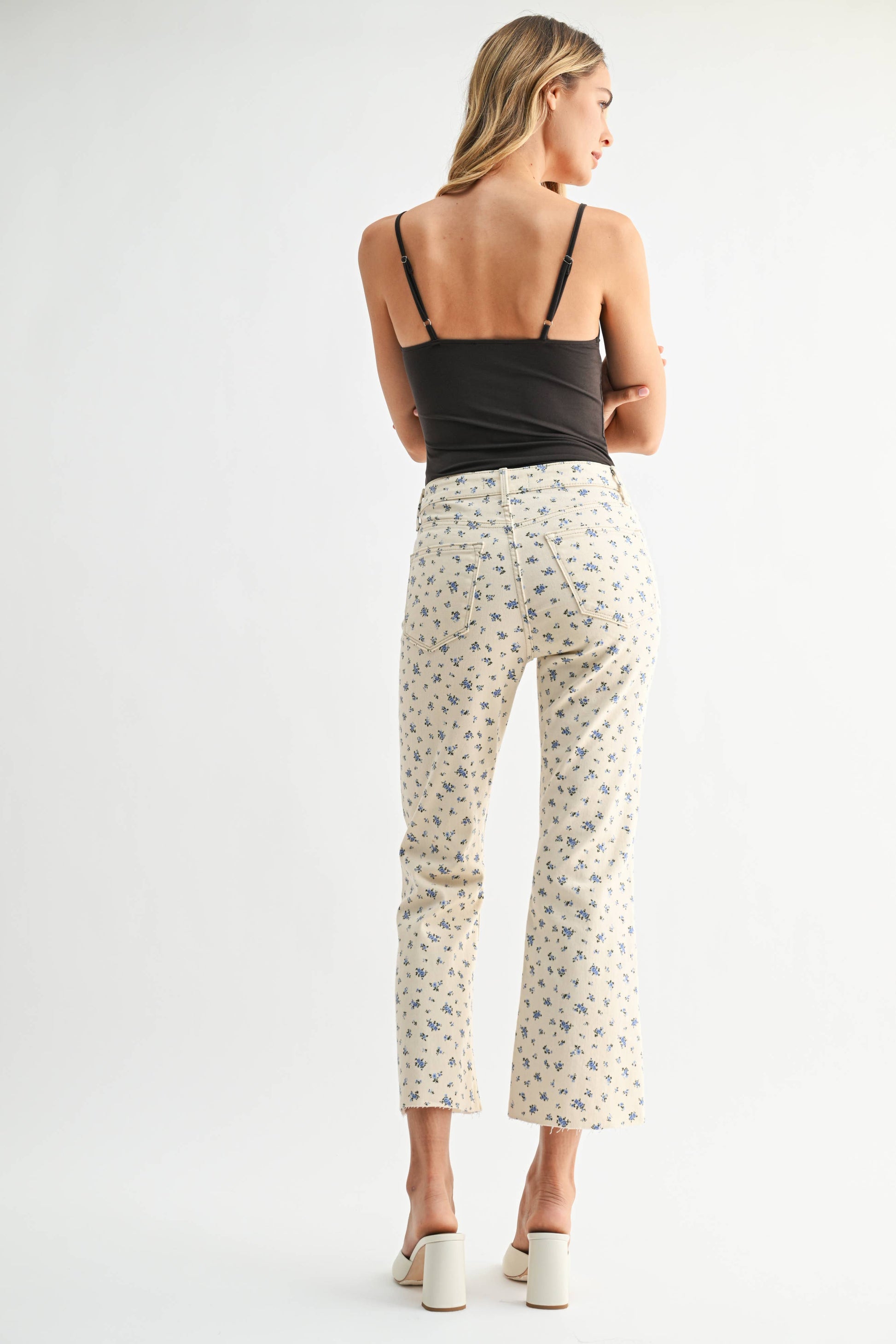 Woman wearing a black top and white floral pants on a white background