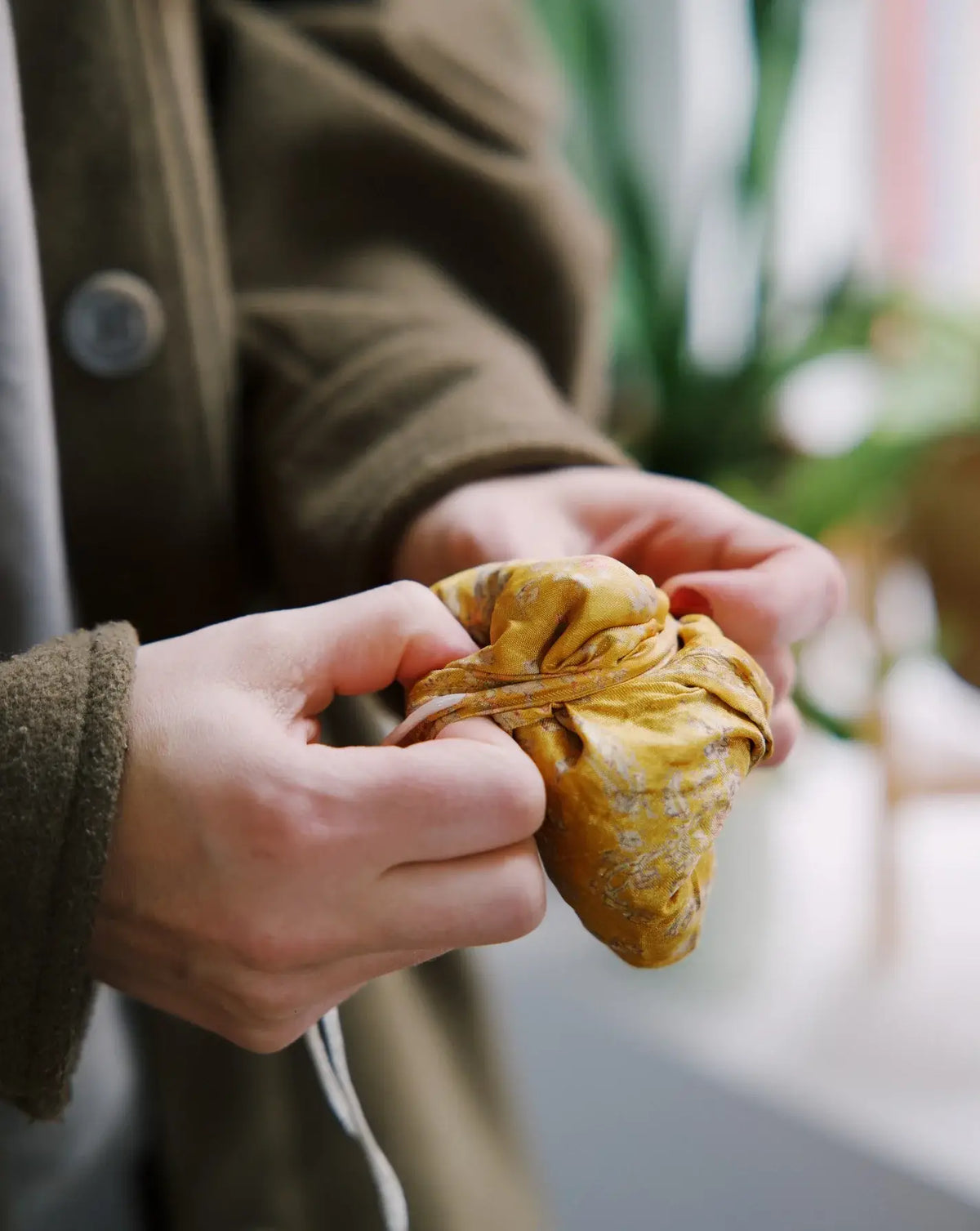 Person holding a yellow knitted item with a blurred background