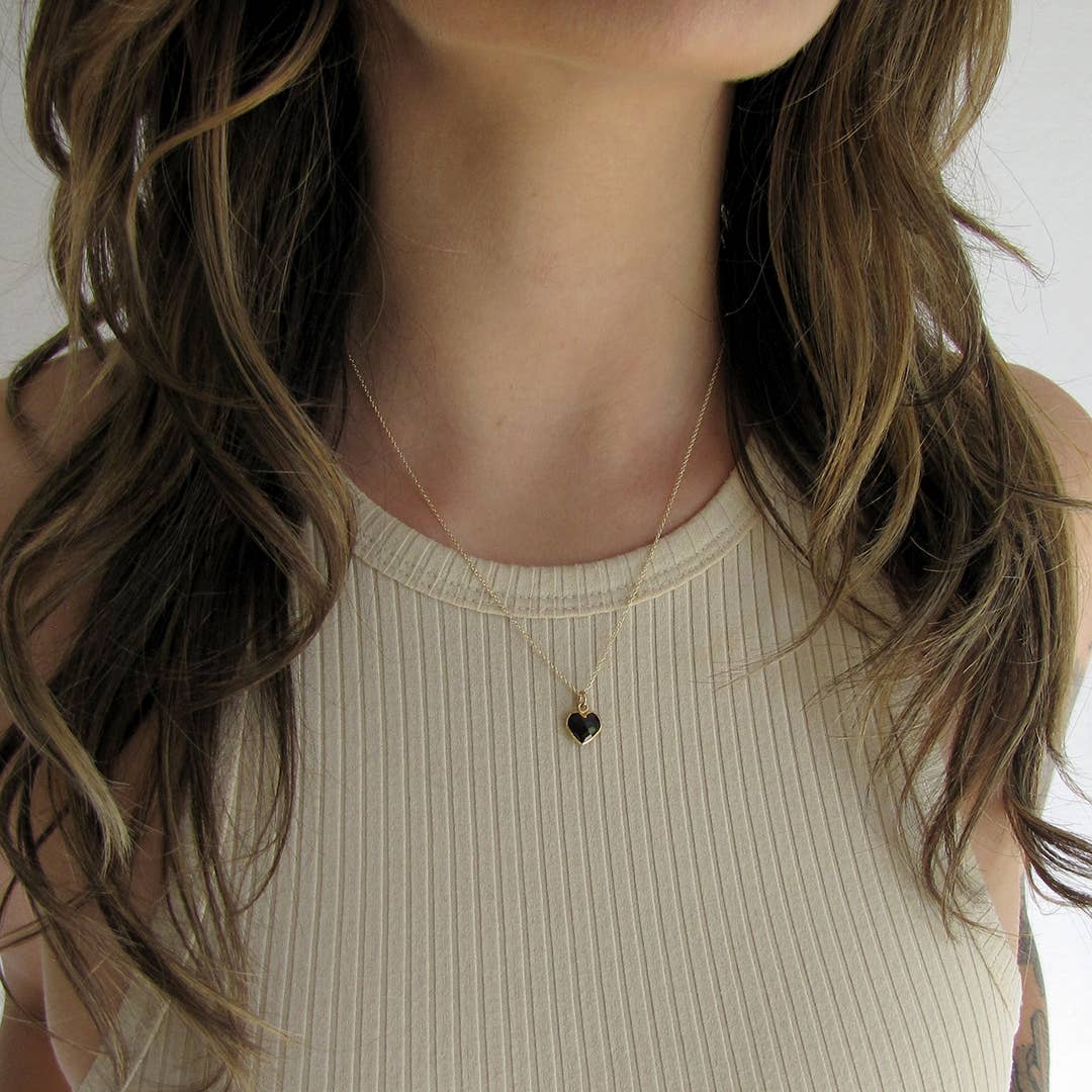 Necklace with a heart pendant worn by a person with long hair.