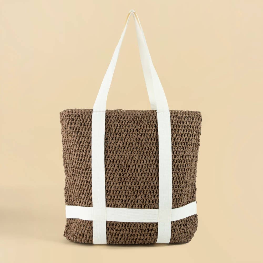 Brown woven tote bag with white straps on a beige background