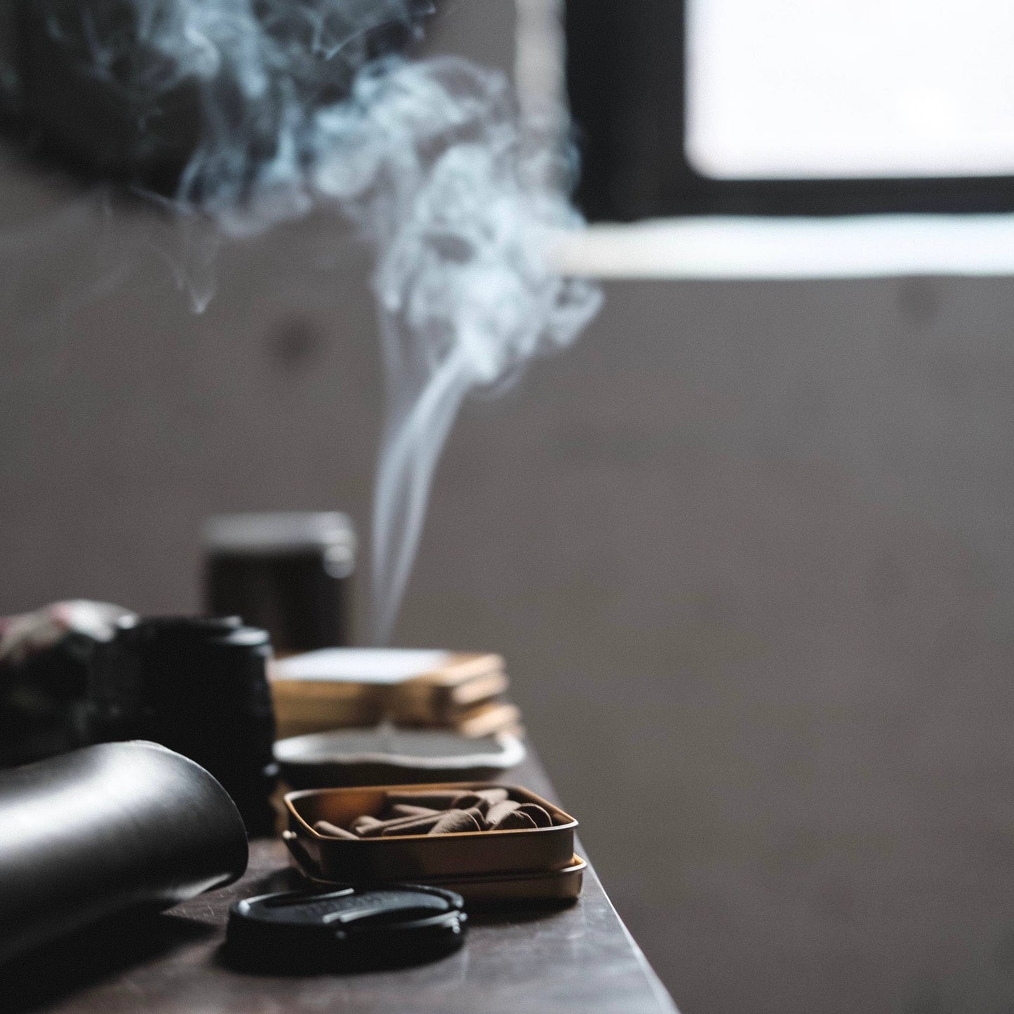 Smoking activity with smoke rising from a pipe on a wooden surface.