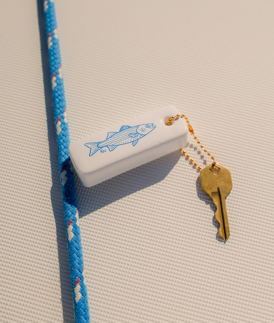 White device with blue fish design, blue rope, and gold key on a textured beige surface