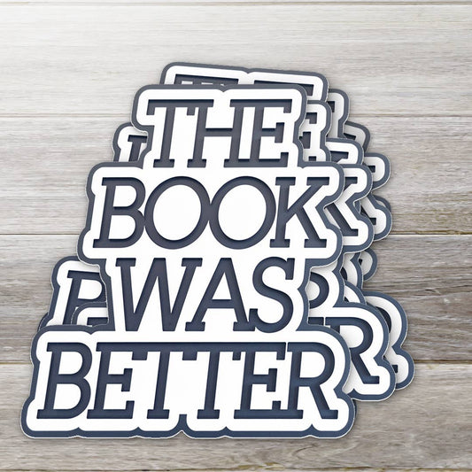 Stack of 'The Book Was Better' stickers on a wooden surface