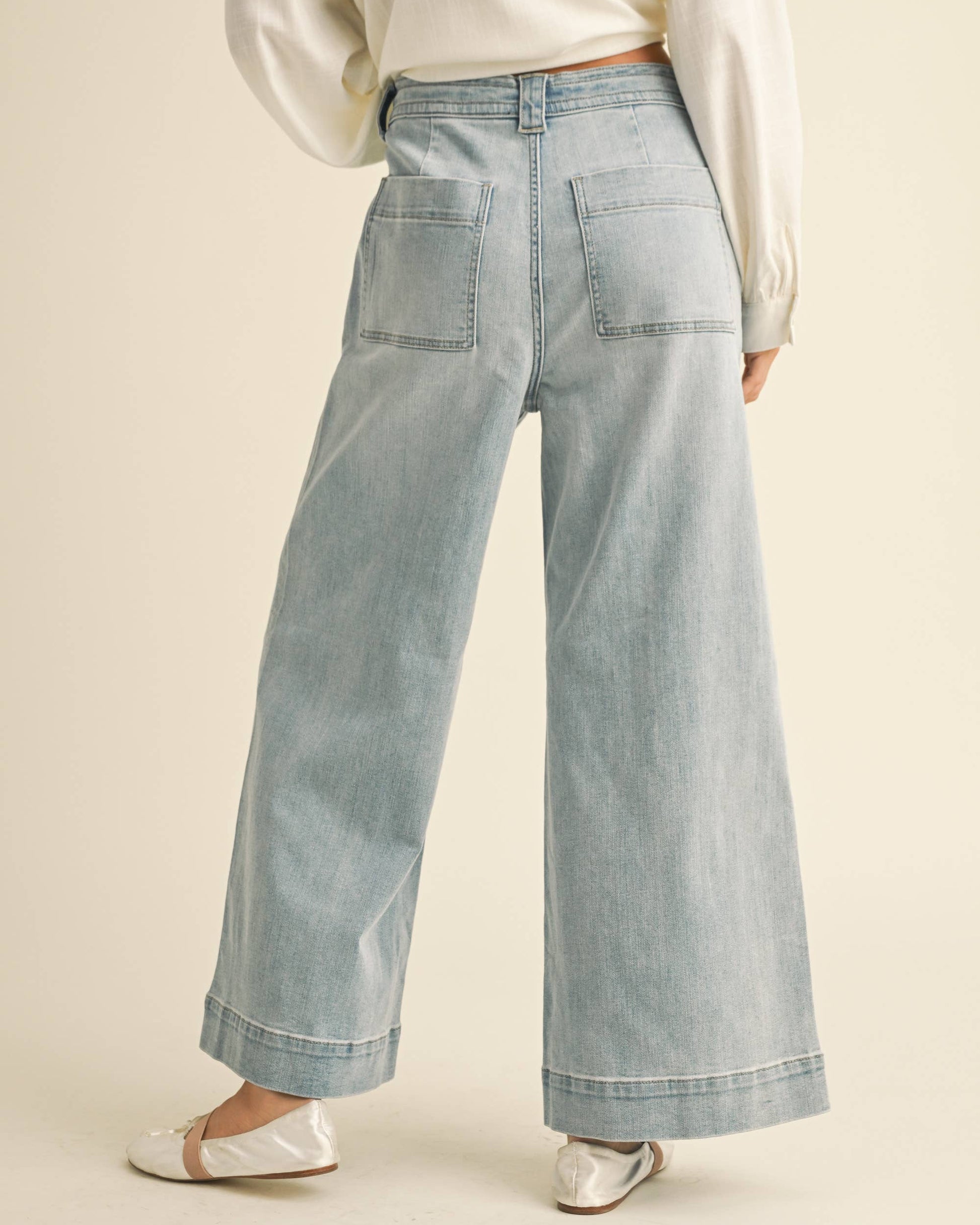 Light blue denim pants worn by a person on a beige background
