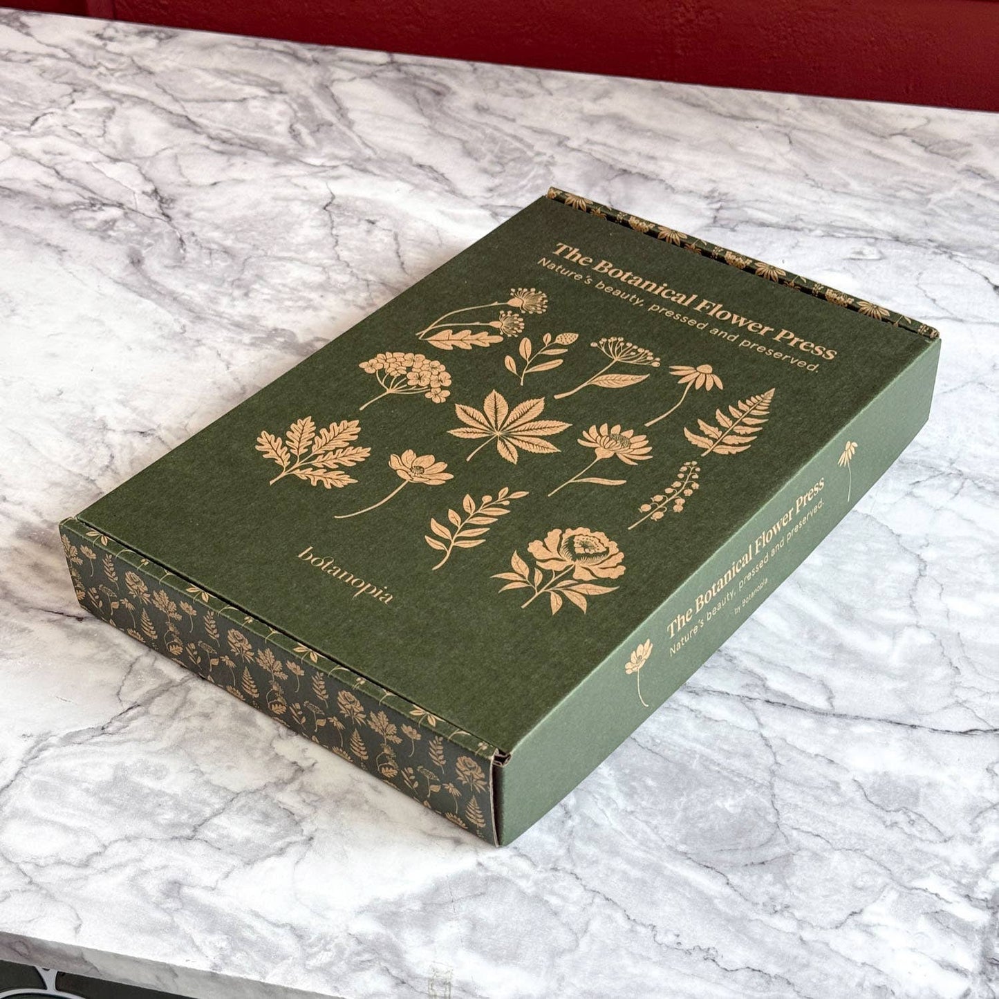 Green box with floral designs on a marble surface