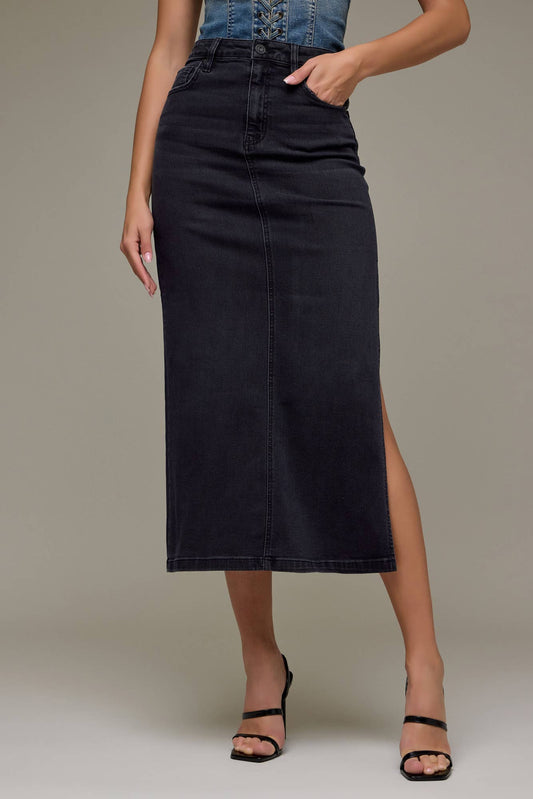 Person wearing a black denim skirt with a plain background
