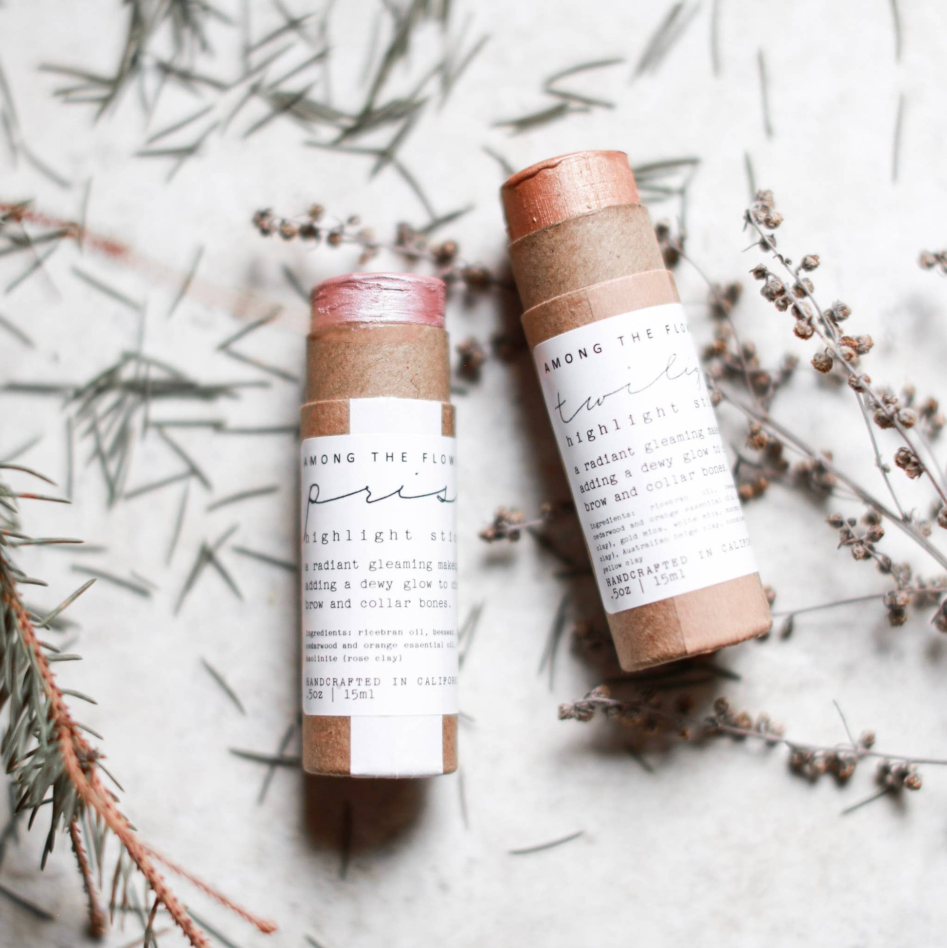Two skincare products with cardboard tubes on a light background with dried plants.