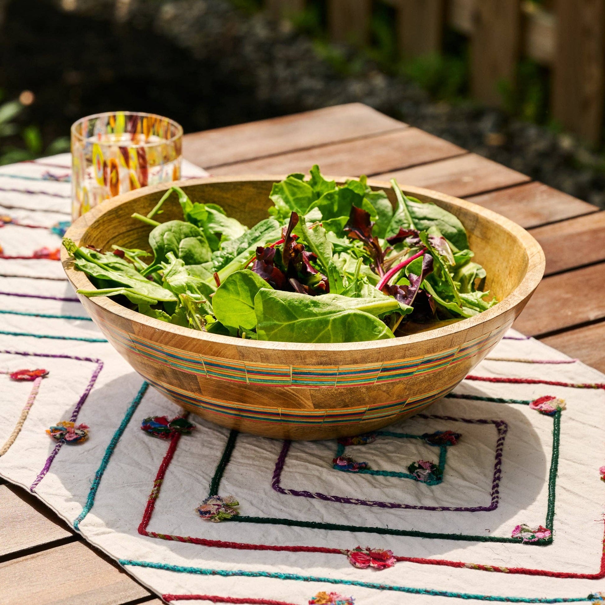 Wooden bowl of salad on a decorative tablecloth outdoors