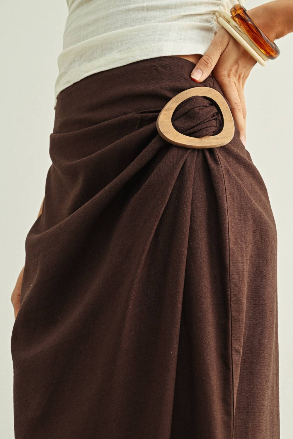 Brown wrap skirt with wooden belt on a plain background