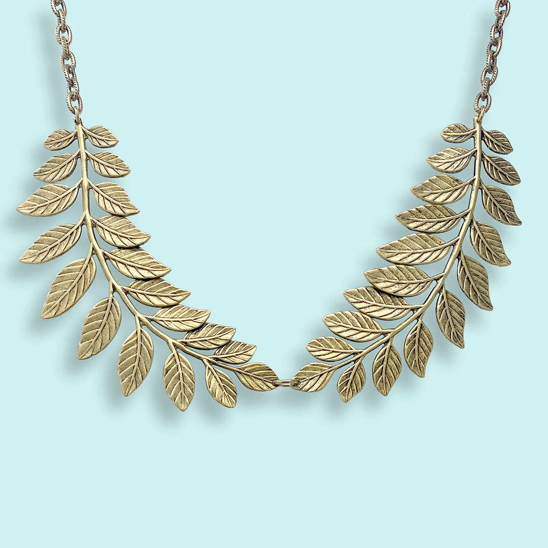 Gold leaf necklace on a light blue background