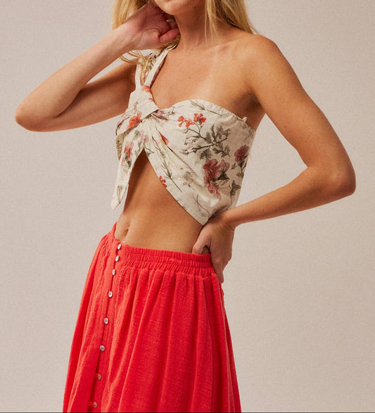 Woman wearing a floral top and red skirt against a plain background
