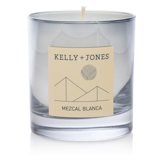 Clear glass candle with a beige label featuring 'Kelly + Jones' and 'Mezcal Blanca' on a white background.
