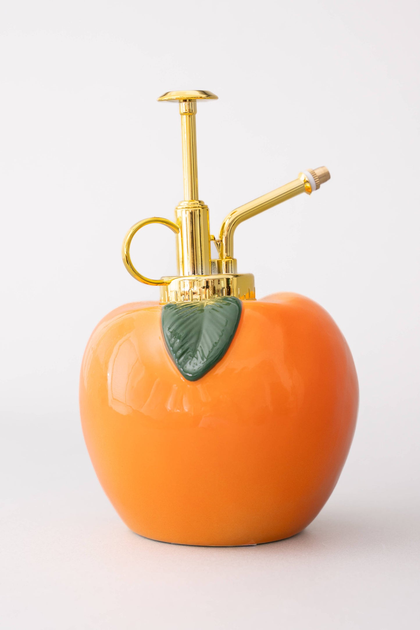 Pumpkin-shaped spray bottle with gold nozzle on a white background