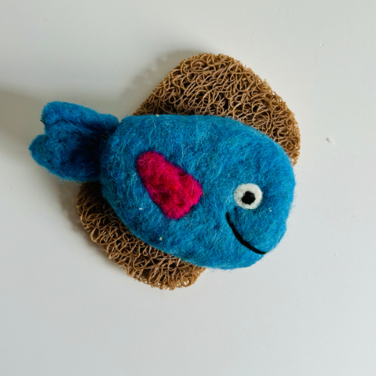 Blue fish-shaped object with a pink heart on a textured surface