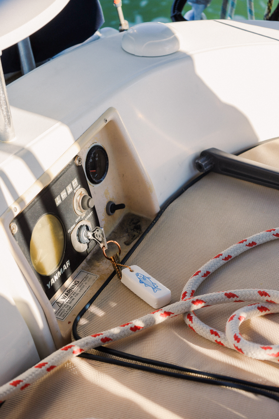 Close-up of a boat's control panel with a rope and keychain on a white surface.