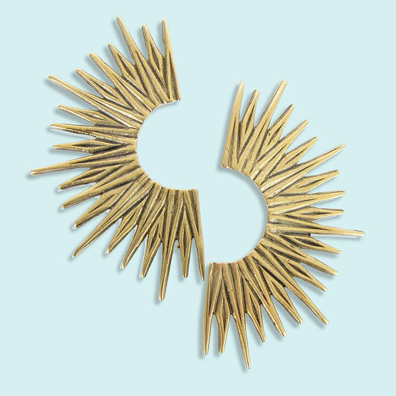 Gold sunburst earrings on a light blue background