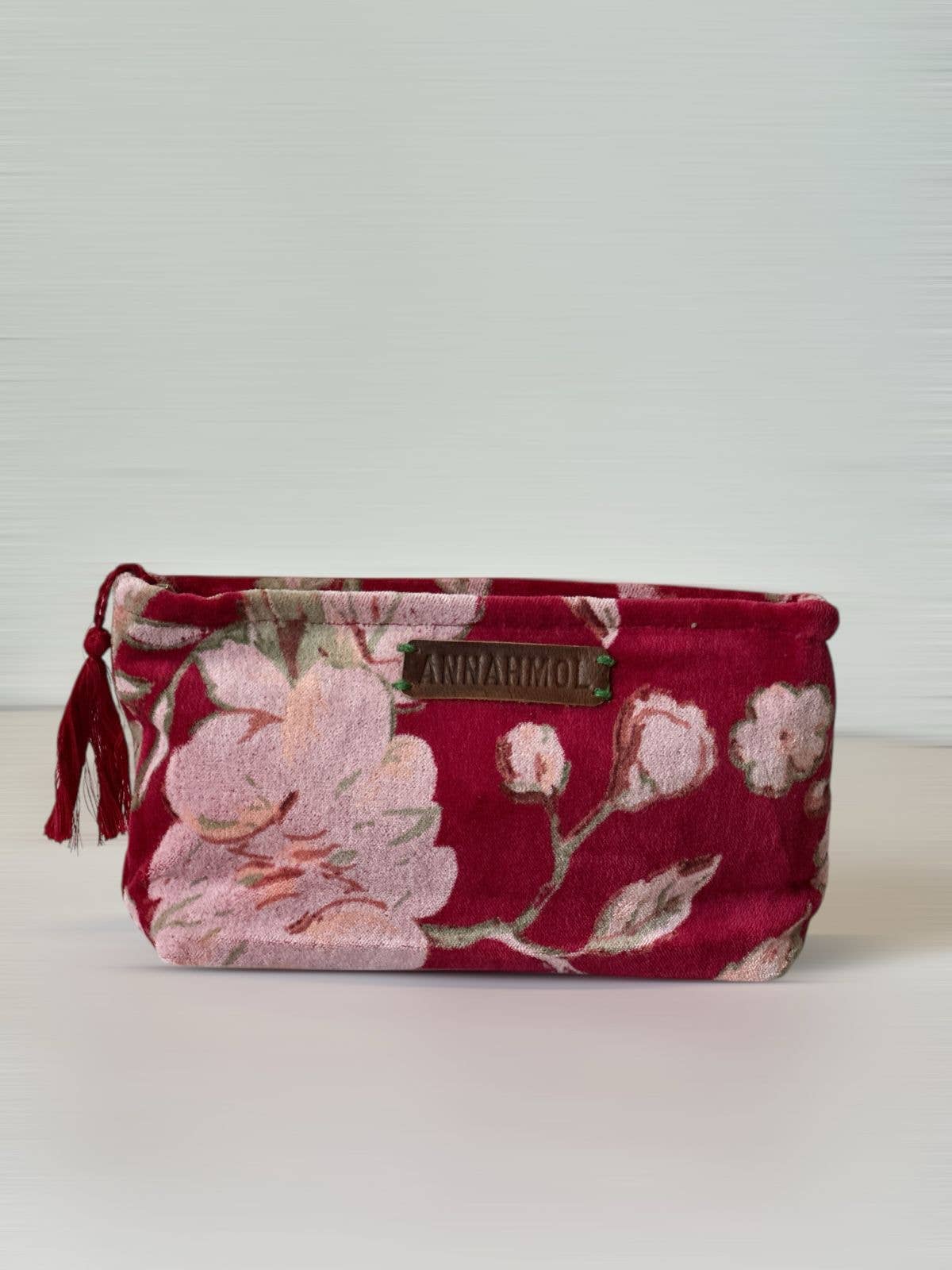 Floral-patterned pouch with a brand label on a light background