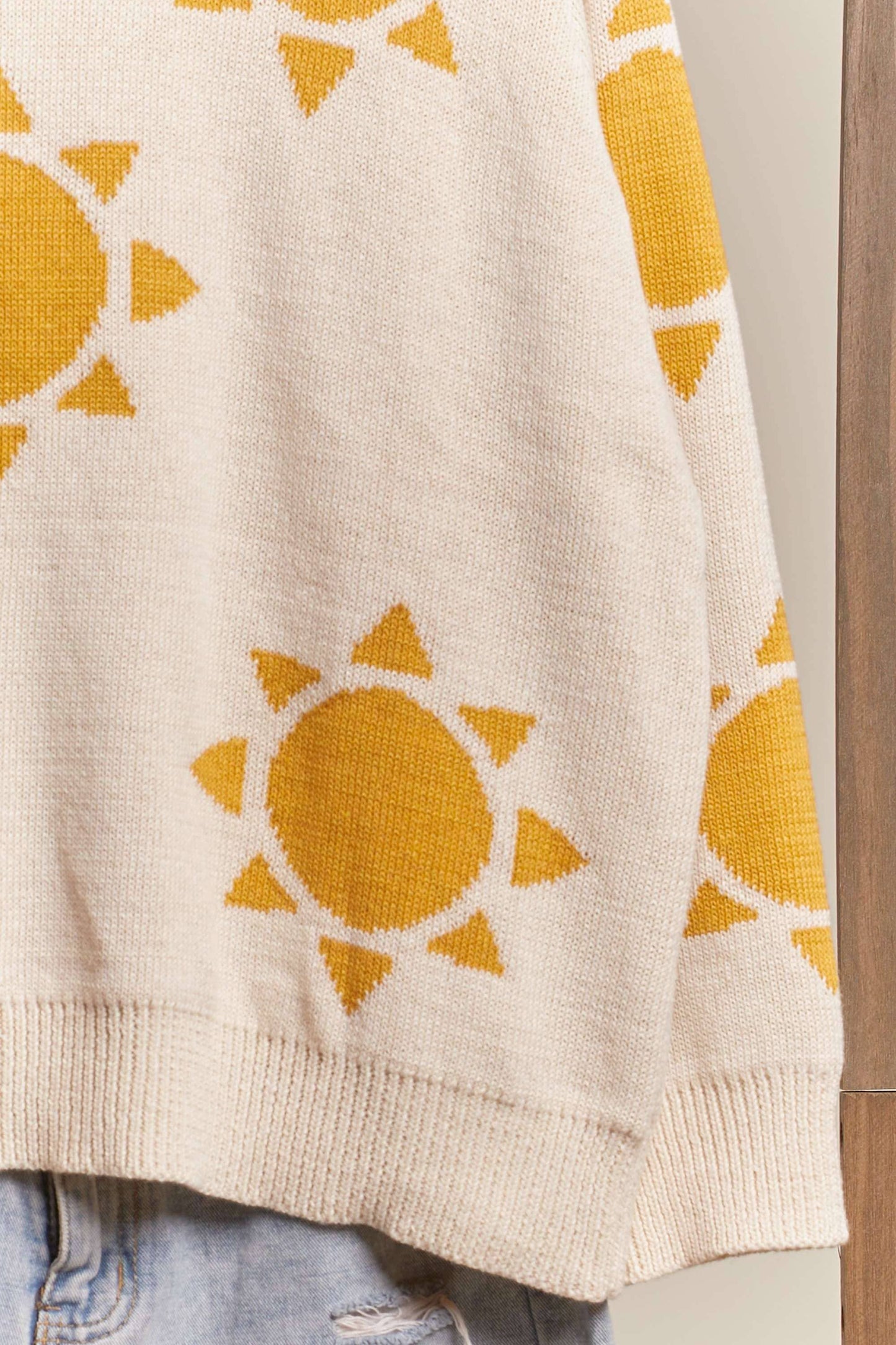Beige sweater with yellow sun patterns on a neutral background