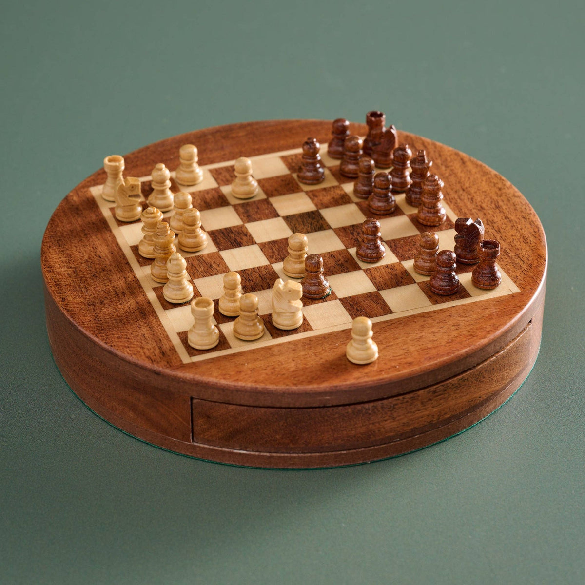 Wooden chessboard with pieces on a green background
