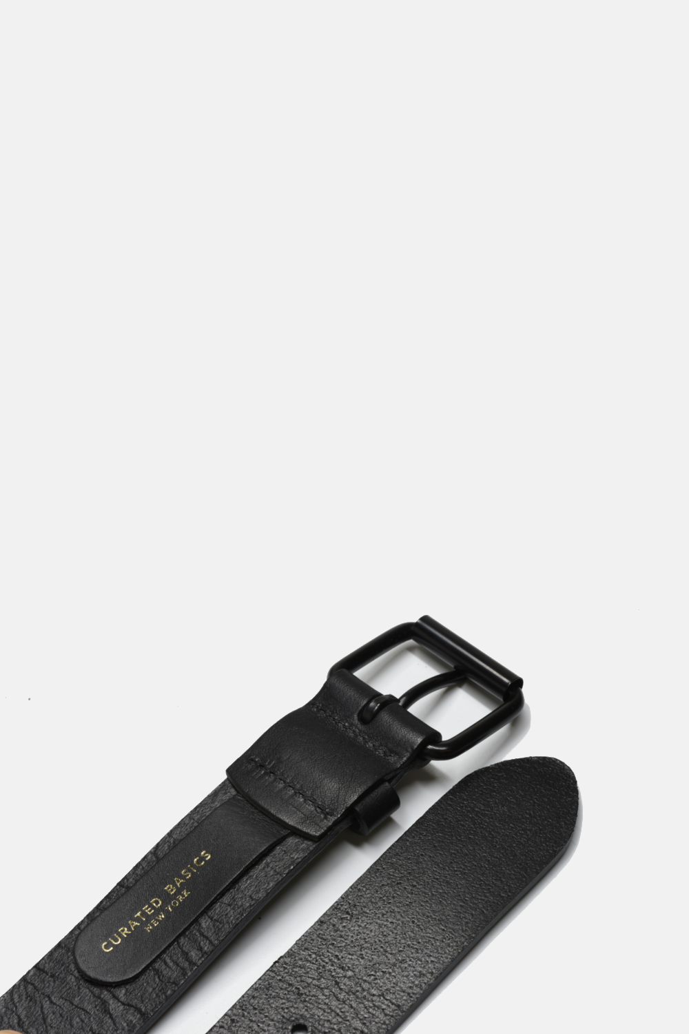Black leather belt with a buckle on a light gray background