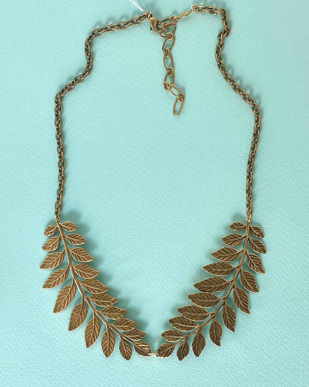 Gold leaf necklace on a light blue background