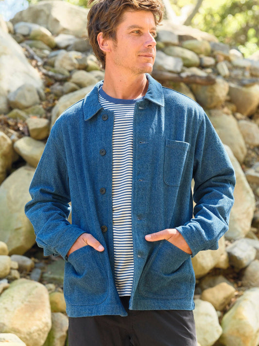 Man wearing a blue jacket standing among rocks