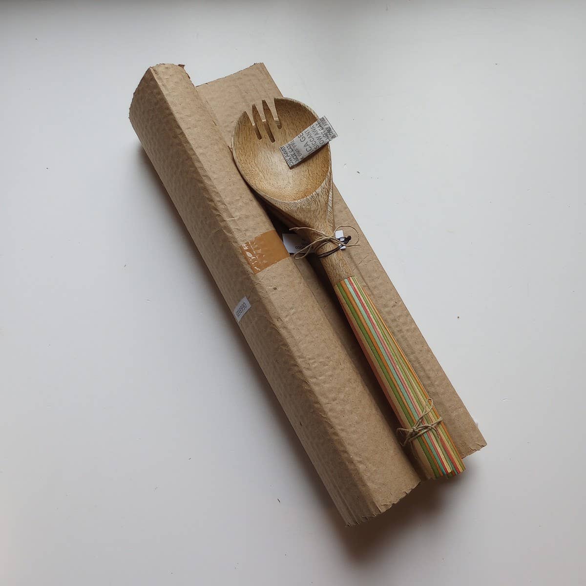 Set of wooden spoon and fork in a cardboard box on a white background