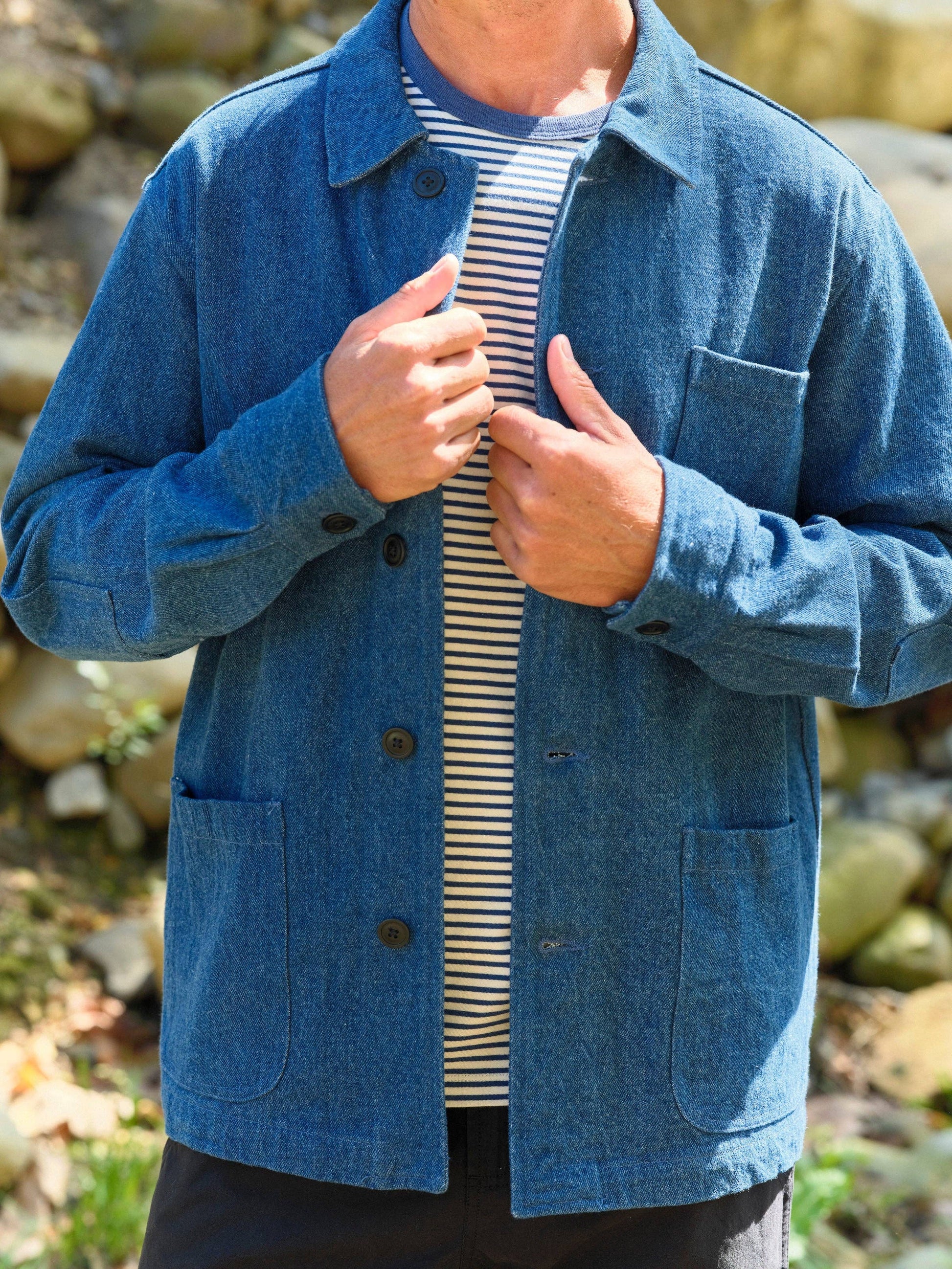 Person wearing a blue jacket over a striped shirt with a natural background