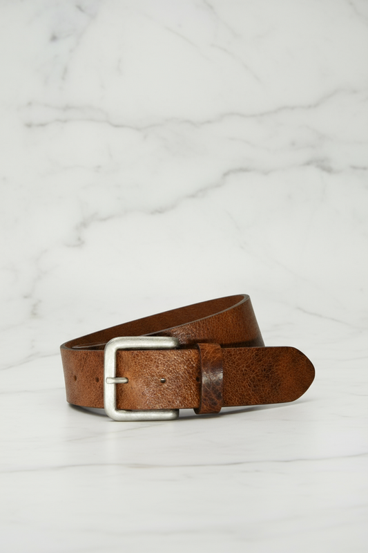Brown leather belt with silver buckle on a marble surface