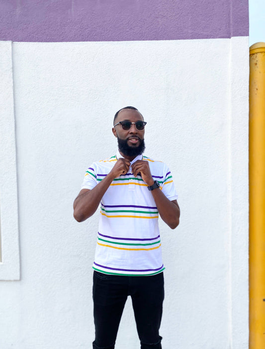 Man wearing a striped shirt standing against a white wall with a yellow pole.