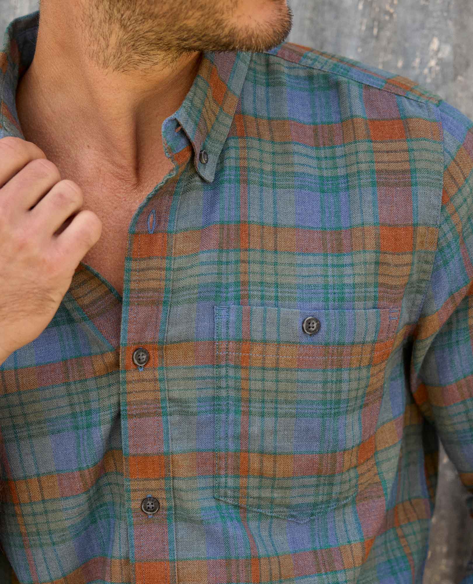 Close-up of a person wearing a plaid shirt with a neutral background
