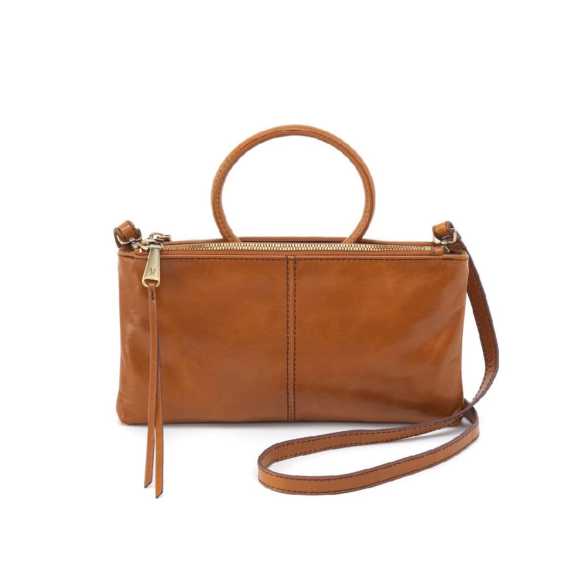 A tan leather handbag with a top handle, a zippered top closure, a side tassel pull, and an adjustable shoulder strap, shown against a plain white background.