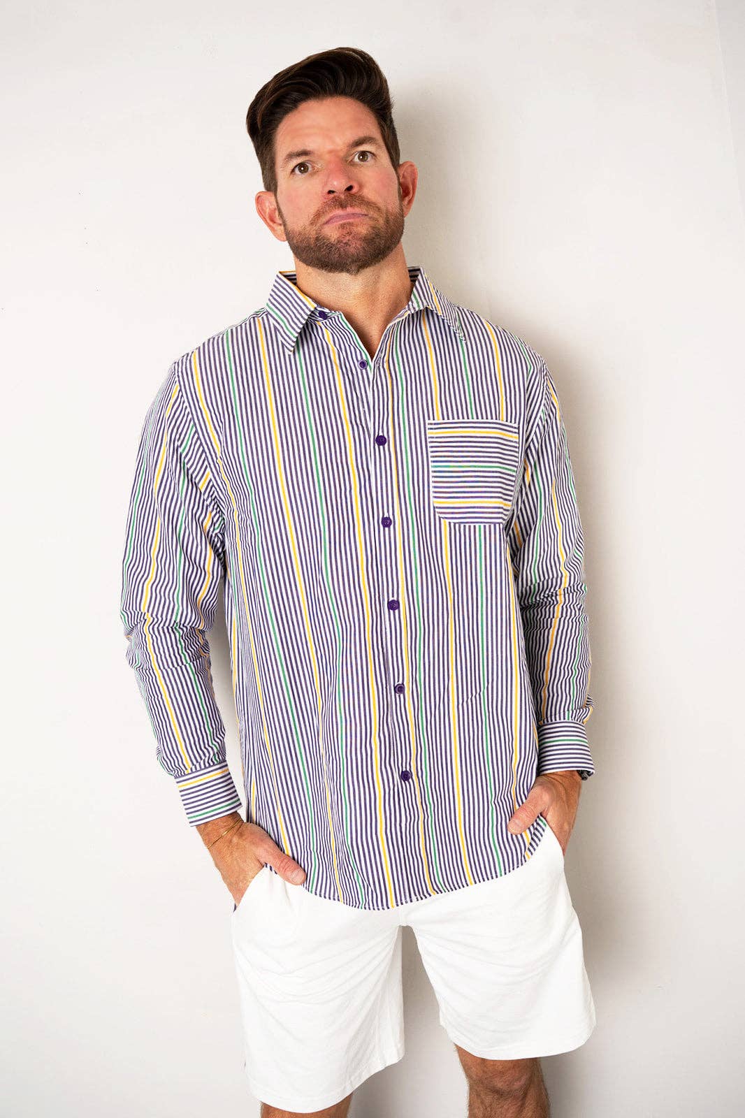 Man wearing a striped shirt and white shorts against a plain background