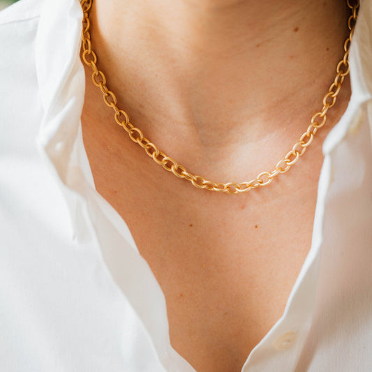 Gold chain necklace on a person wearing a white shirt