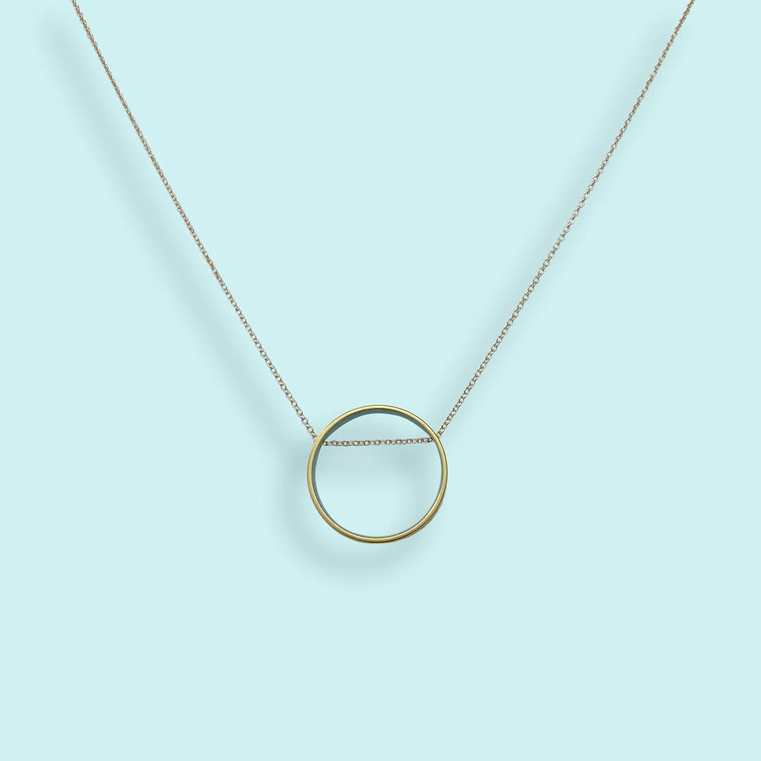 Gold circle pendant necklace on a light blue background
