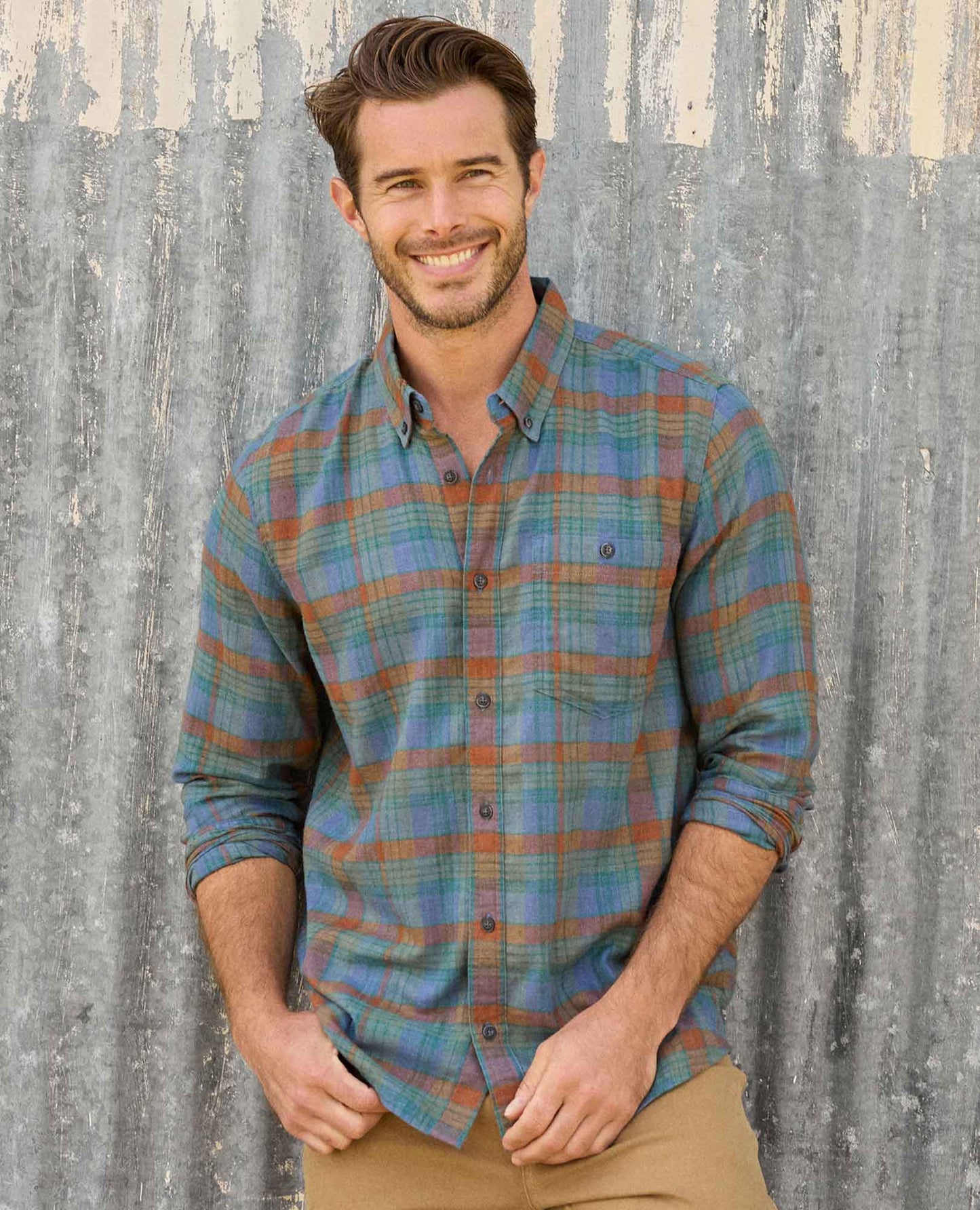 Man wearing a plaid shirt against a rustic wooden background