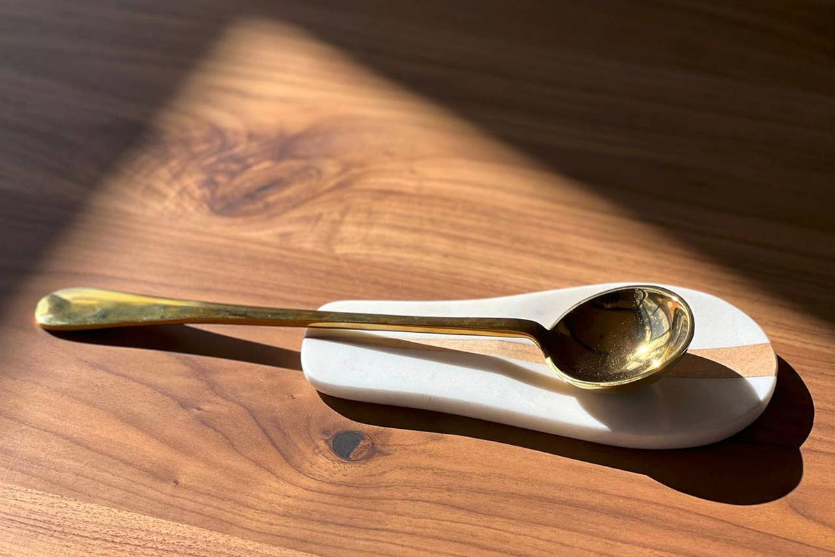 Gold spoon on a white stand on a wooden surface