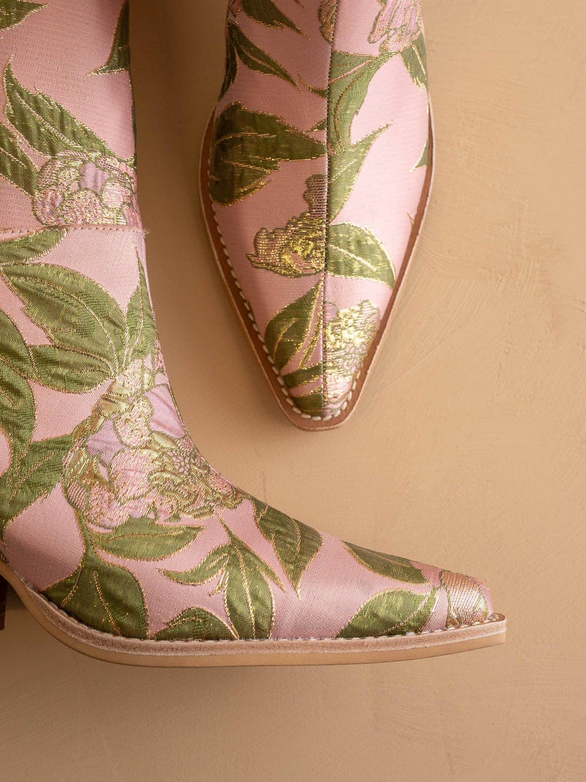 Pink shoes with green leaf pattern on a beige background