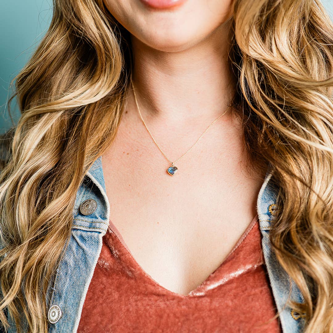 Person wearing a necklace with a heart-shaped pendant, close-up of neck and chest area.