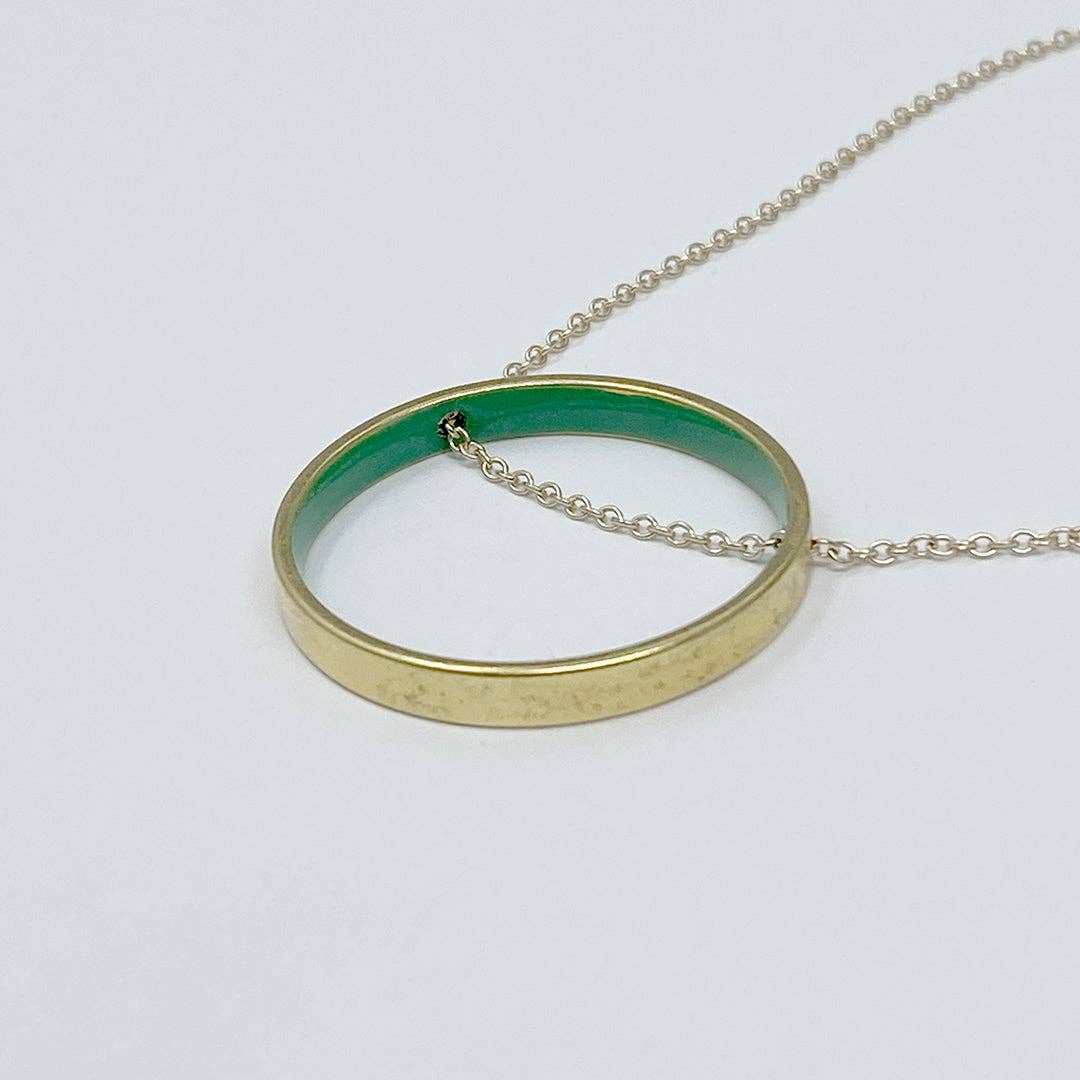Gold ring pendant with green interior on a white background