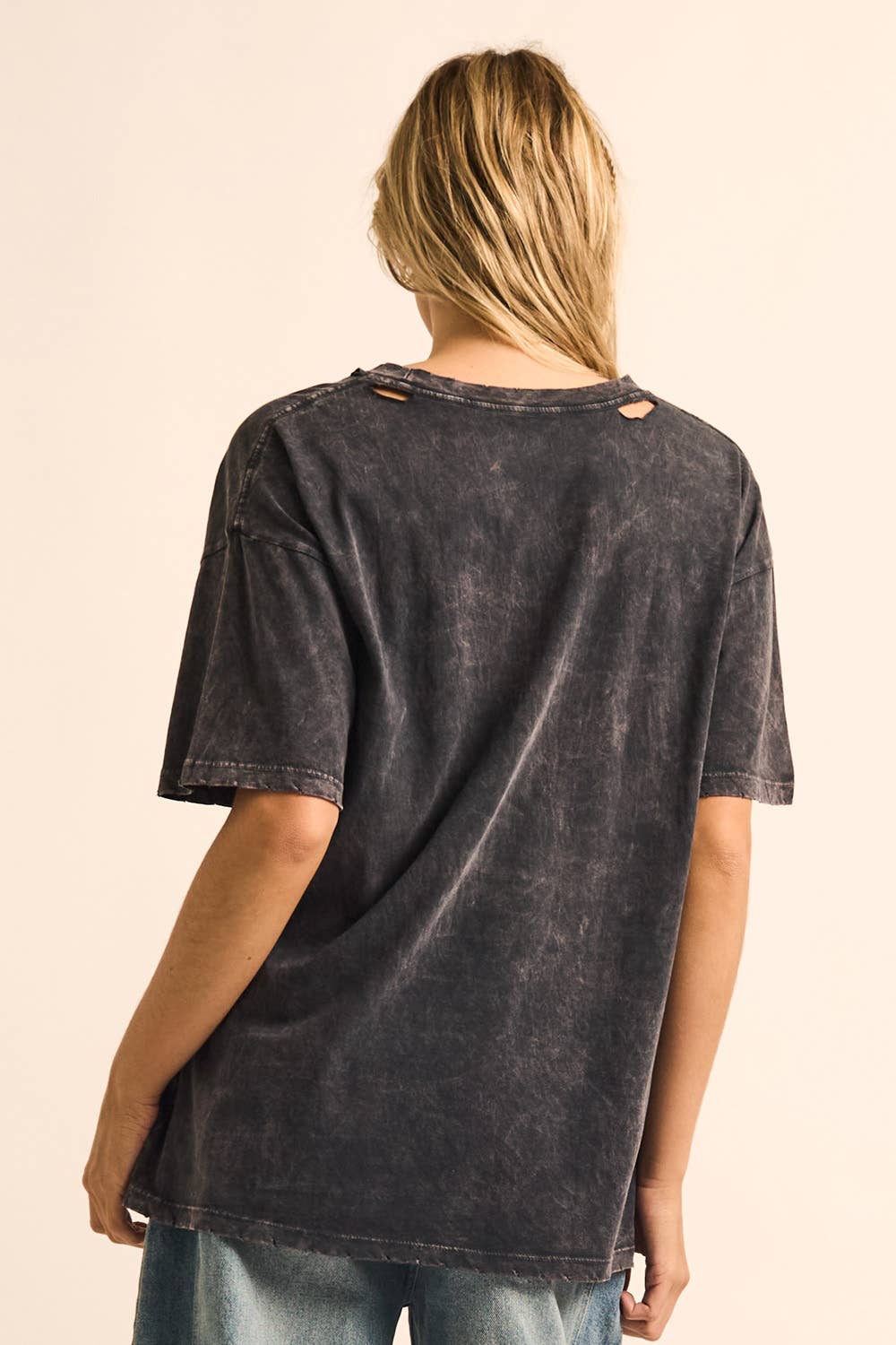 Person wearing a black distressed t-shirt on a beige background