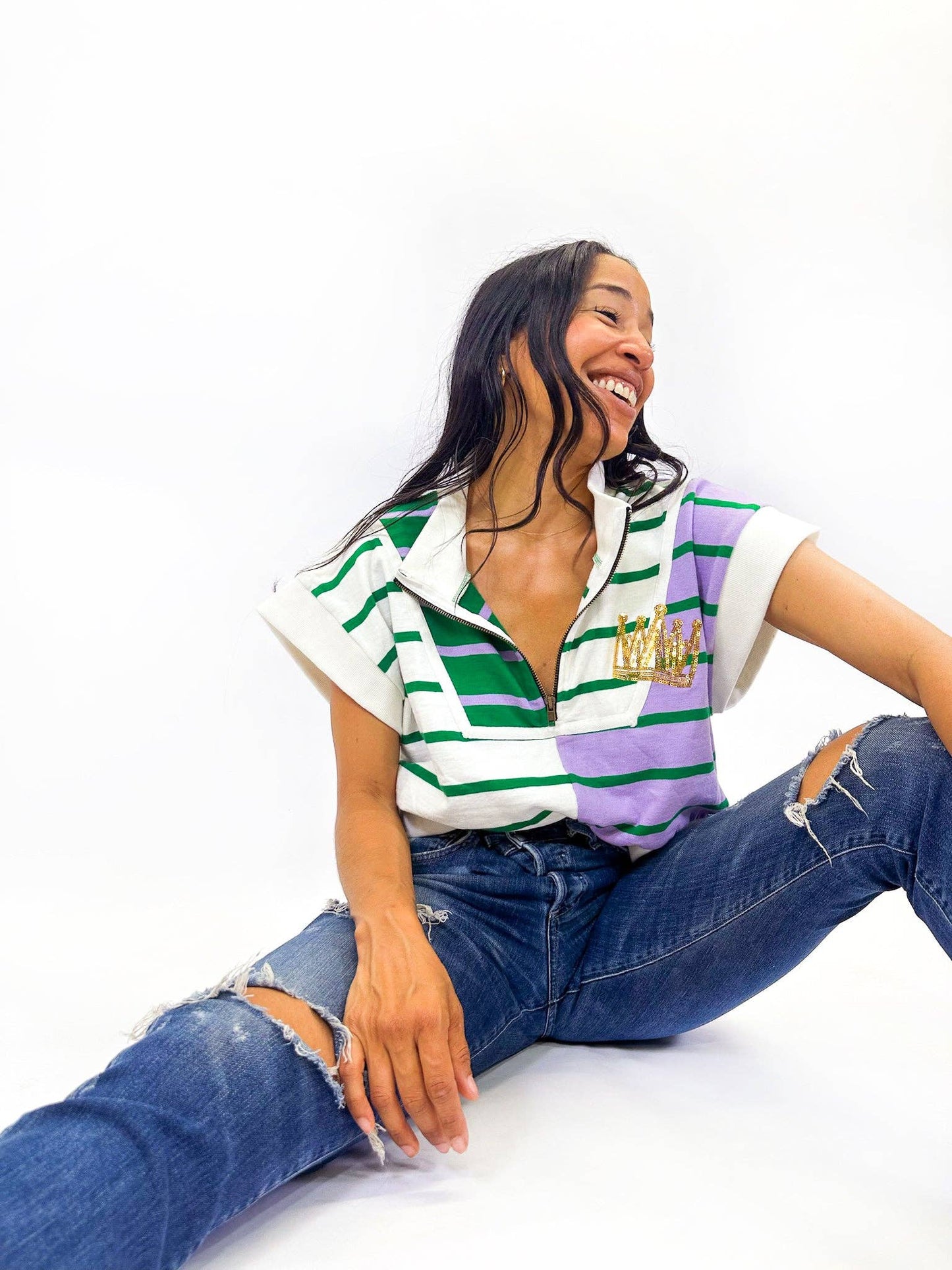 Woman wearing a striped shirt and jeans sitting on a white background