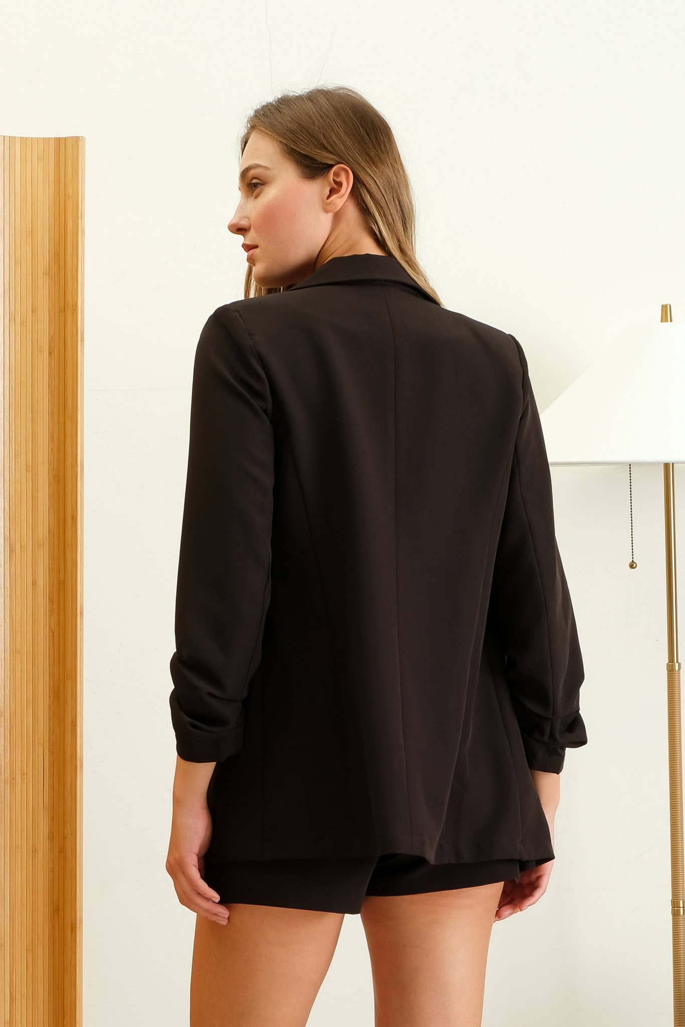 Woman wearing a black blouse with long sleeves in a minimal indoor setting