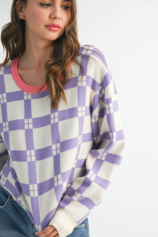 Woman wearing a purple and white checkered sweater with a pink collar on a white background