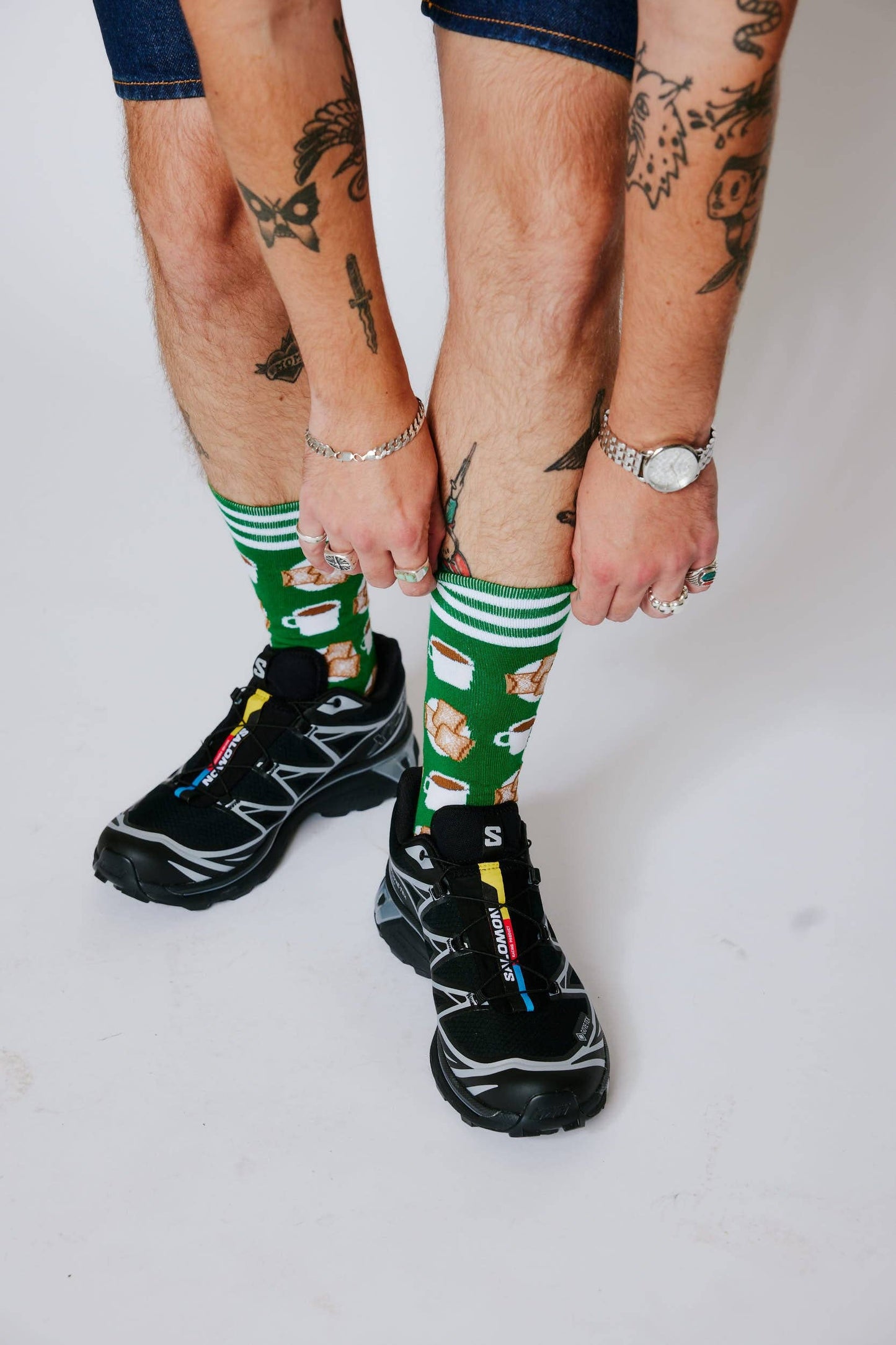 Two pairs of feet wearing green socks with patterns, standing on a white background.