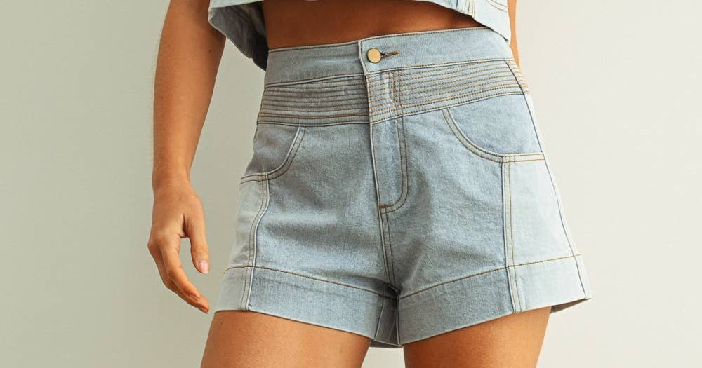Denim shorts worn by a person on a plain background